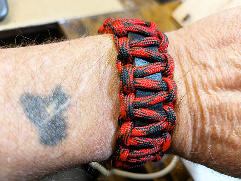 Paracord bracelet in black and red with leather strap.
